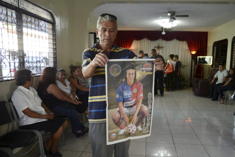 A man holds up a poster next to a coffin with the body of Alfredo Pacheco, during his wake in Santa Ana, El Salvador, December 27, 2015. u00e2u20acu201d Reuters pic
