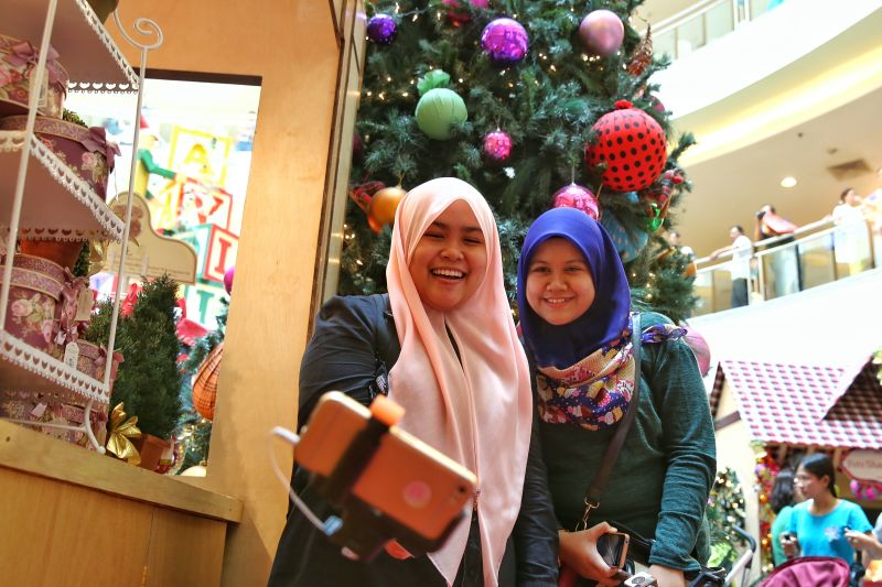 Shoppers pose in front of the Christmas tree at Mid Valley Megamall in Kuala Lumpur, December 24, 2015. u00e2u20acu2022 Picture by Saw Siow Feng