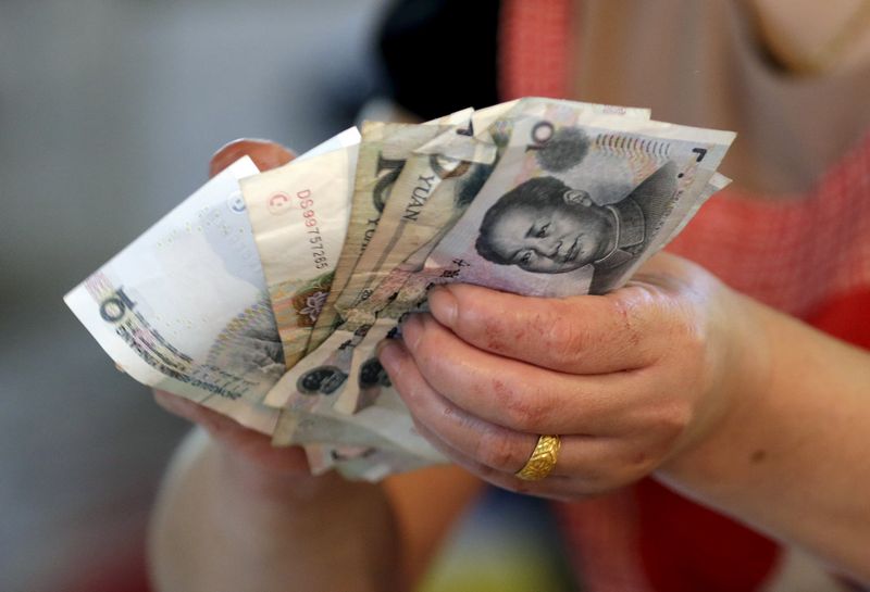 A vendor holds Chinese Yuan notes at a market in Beijing in this August 12, 2015 file photo. u00e2u20acu201d Reuters pic