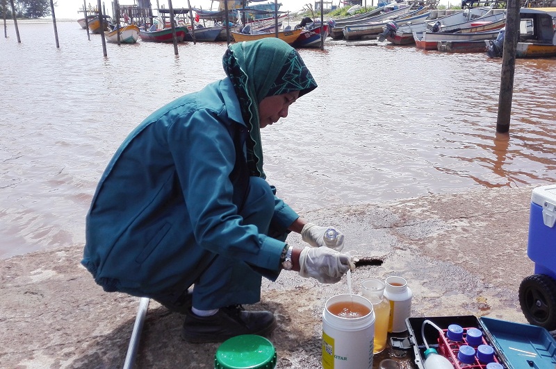 An officer from the Environment Department collects water samples from Sungai Balok which has turned red, believed due to bauxite pollution, at Kuantan, December 3, 2015. u00e2u20acu201d Bernama pic