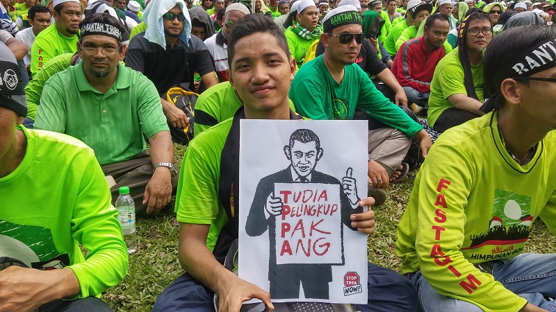 Imaam Abd Aziz, 18, from Ampang PAS holding a banner showing US President Barack Obama as an opportunist during the anti-TPPA rally in Kuala Lumpur on January 23, 2016. u00e2u20acu201d Picture by Yiswaree Palansamy