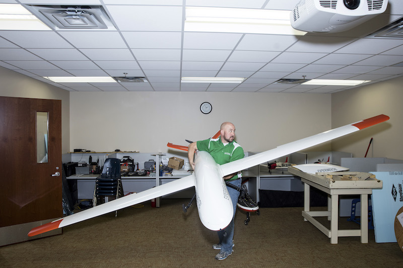 Ryan Walsh, an instructor at the Grand Forks Air Force Base, makes sure that the wings of a SandShark unmanned aircraft have clearance in a classroom at the Grand Forks Air Force Base in Grand Forks, North Dakota, November 24, 2015. — Picture by Tim Gruber/The New York Times