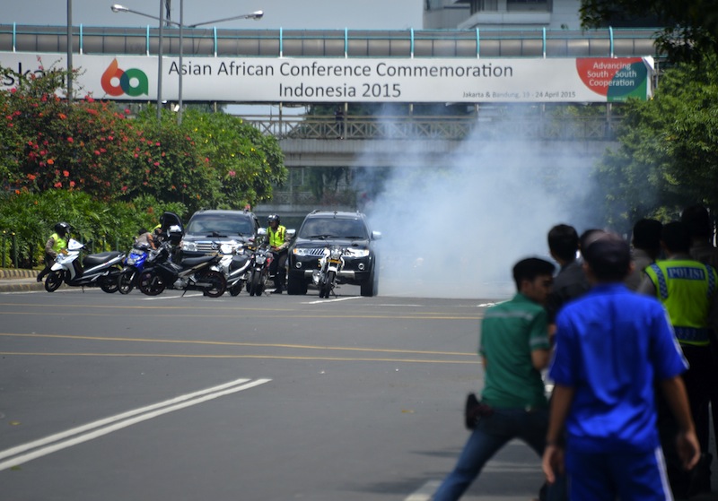 Police hide behind vehicles during an exchange of gunfire with suspects hiding near a Starbucks cafe when another blast happens in Jakarta on January 14, 2016. u00e2u20acu201d AFP pic
