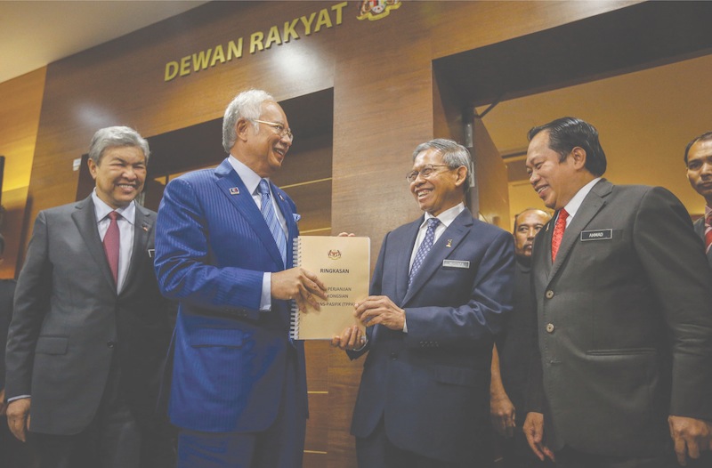Mustapa Mohamed (second from right) hands over a summary of the TPPA to Prime Minister Datuk Seri Najib Razak outside the Dewan Rakyat on Wednesday. — Picture by Firdaus Latif