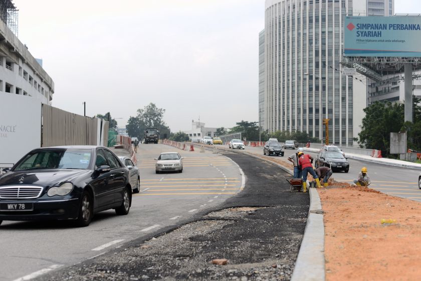 Workers patch the road near the Petaling Jaya New Town. The one-way loop project is scheduled for completion in August. u00e2u20acu201d Malay Mail pic