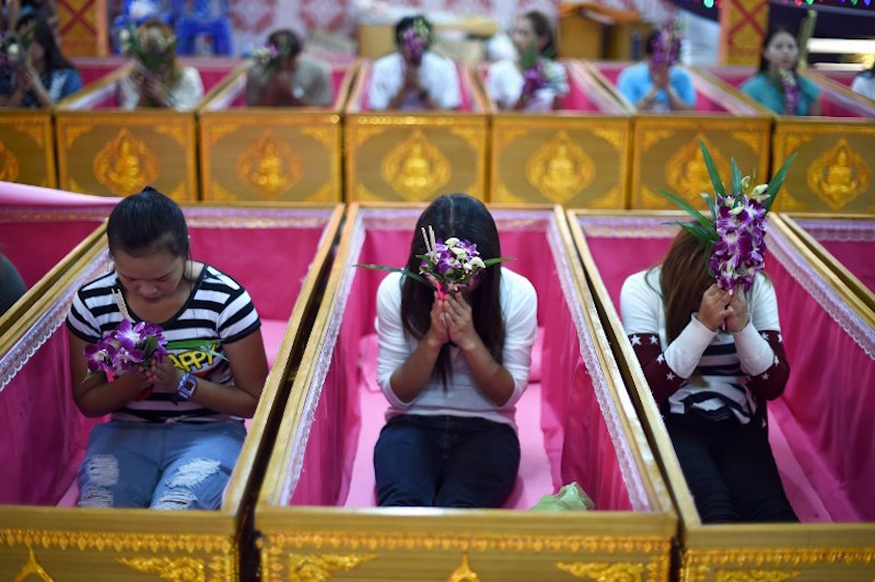 Devotees offering prayers as they sit in coffins at the end of a group resurrection ceremony at the Wat Ta Kien Buddhist temple in Nonthaburi on the outskirts of Bangkok January 16, 2016. u00e2u20acu201d AFP pic