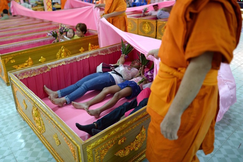 Devotees lying in coffins as Buddhist monks drape a pink sheet over during a group resurrection ceremony at the Wat Ta Kien Buddhist temple in Nonthaburi on the outskirts of Bangkok January 16, 2016. — AFP pic