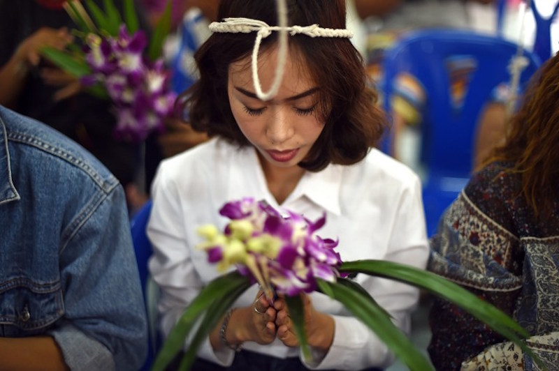 Devotees listening to prayers with sacred ropes wrapped around their heads at the start of a group resurrection ceremony at the Wat Ta Kien Buddhist temple in Nonthaburi on the outskirts of Bangkok January 16, 2016. — AFP pic
