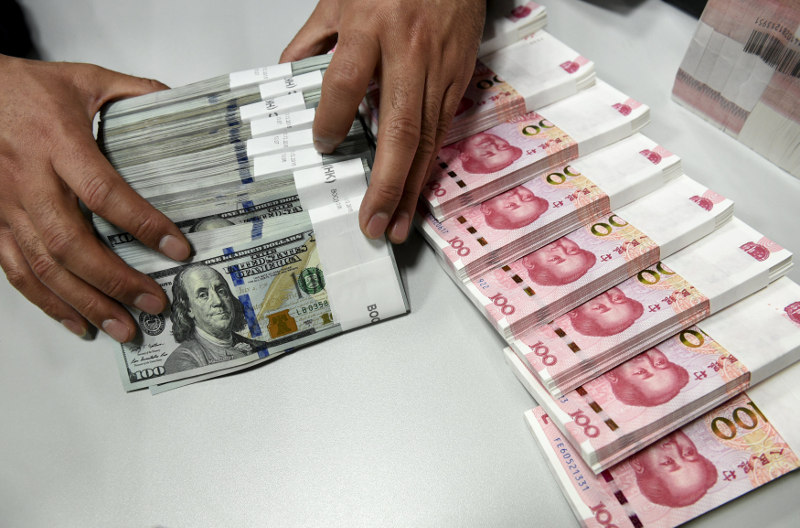 A clerk counts Chinese yuan and US dollar banknotes at a branch of Bank of China in Taiyuan, Shanxi province, China, January 4, 2016. u00e2u20acu201d Reuters pic