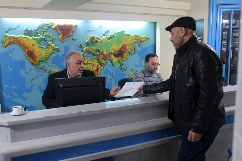 Palestinian travel agent Nabil Shurafa (left) receives a document from a client at his office in Gaza City February 4, 2016. u00e2u20acu201d Reuters pic