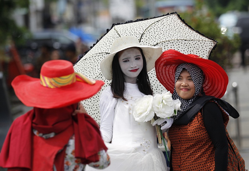 A woman has her picture taken with a street performer (centre) in Kota Tua, or the Old Town, a popular tourist spot in Jakarta, Indonesia February 15, 2016. u00e2u20acu201d Reuters pic
