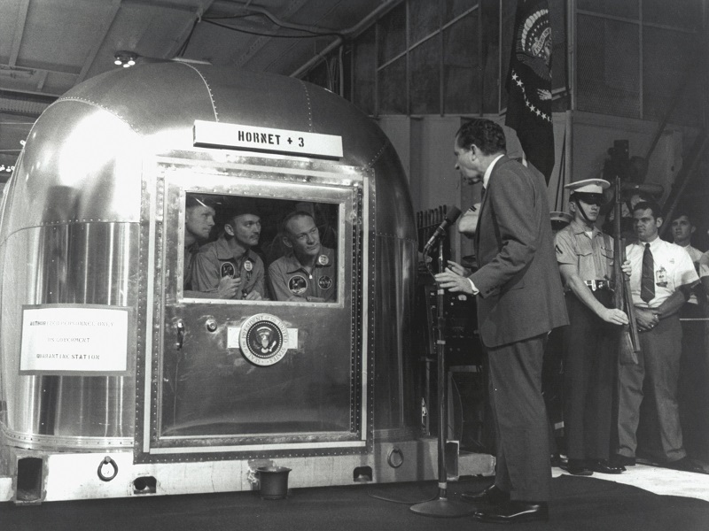 From left: Apollo 11 astronauts Commander Neil Armstrong, Command Module Pilot Michael Collins and Lunar Module Pilot Edwin u00e2u20acu0153Buzzu00e2u20acu009d Aldrin Jr, inside the Mobile Quarantine Facility aboard the USS Hornet, as President Richard Nixon welcomes them back to