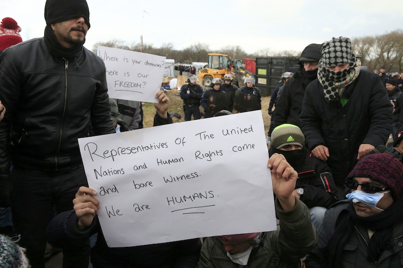 French CRS riot police stand near Iranian migrants with a message during a protest against the partial dismantlement of the shanty town called the 'Jungle' in Calais, France, March 2, 2016. — Reuters pic