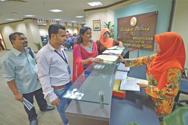 An employer renews work permits of her foreign workers. The presence of migrant workers has made it more difficult for locals to obtain jobs. u00e2u20acu2022 Malay Mail pic
