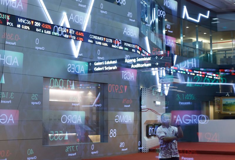 A man uses a mobile device in front of an electronic board showing the stock market index at the Indonesia Stock Exchange (IDX) in Jakarta, February 2, 2016. u00e2u20acu201d Reuters pic