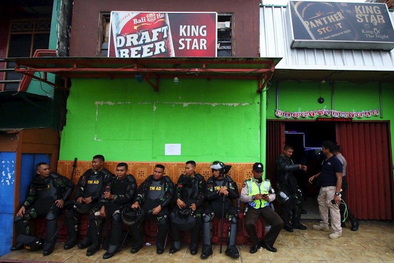 Indonesian soldiers and policeman sit and guard in front of a cafe building at Kalijodo red-light district in Jakarta, Indonesia, February 20, 2016 in this picture taken by Antara Foto. u00e2u20acu201d Reuters pic