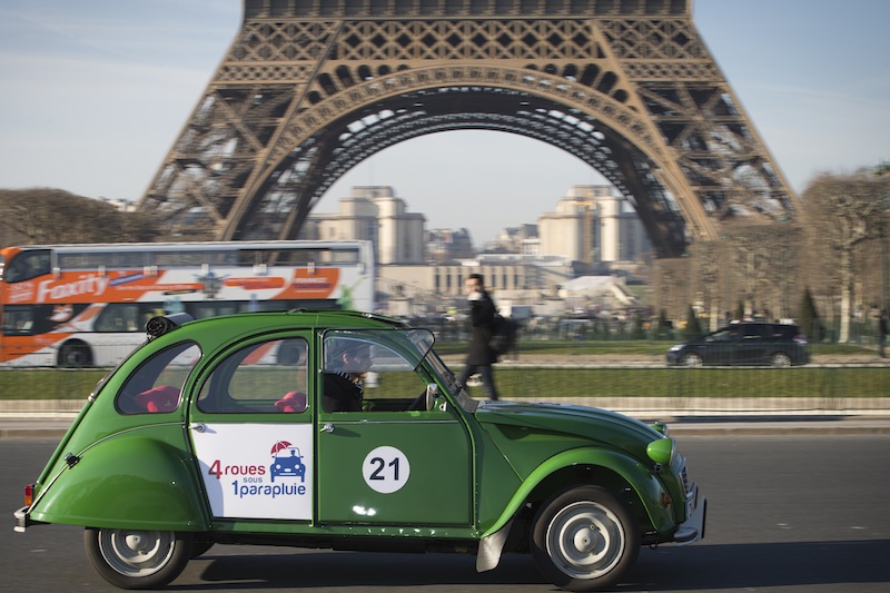 An employee of the French tourist agency '4 roues sous un parapluie' (4 wheels under an umbrella), driving a Citroen 2CV electric car past the Eiffel tower in Paris, on January 21, 2016. u00e2u20acu201d AFP pic