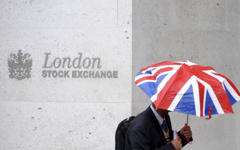 A worker shelters from the rain as he passes the London Stock Exchange in the City of London, Britain, in this October 1, 2008, file photo. REUTERS/Toby Melville/Files