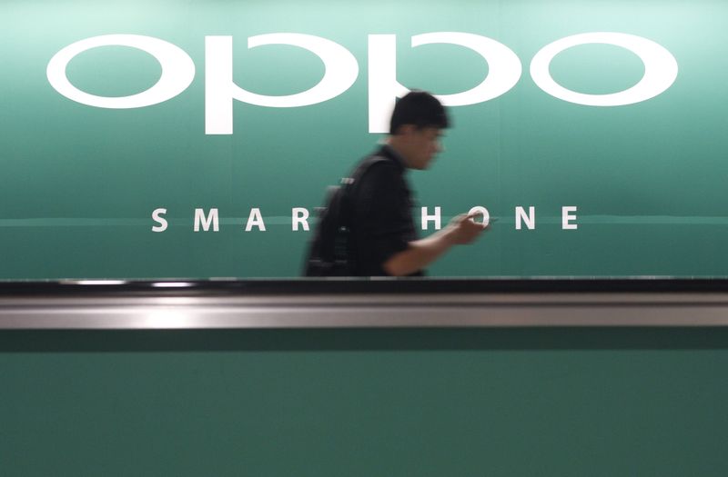 A commuter using his mobile phone passes an advertisement of Chinese smartphone maker Oppo at a train station in Singapore in this May 8, 2014 file photo. u00e2u20acu201d Reuters pic