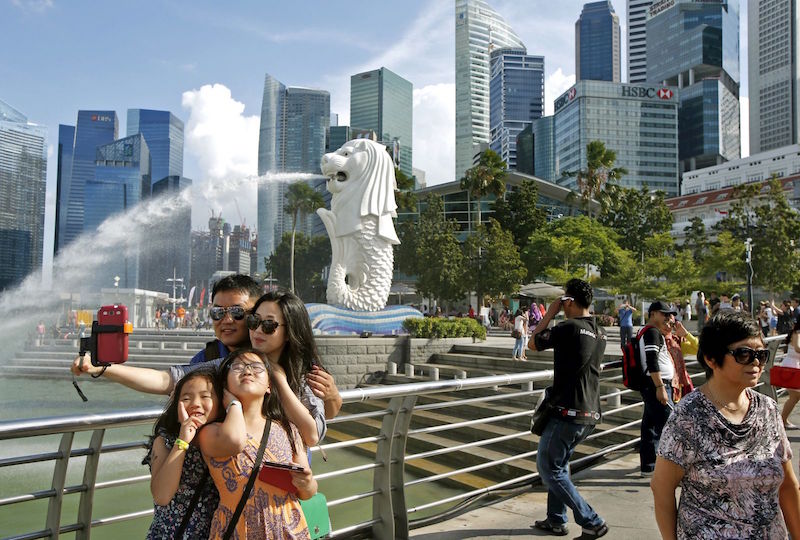 Tourists take photos by the Merlion in Singapore. u00e2u20acu201d Reuters pic