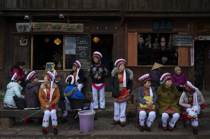 Locals dressed in traditional clothing watch a performance in the square of Sideng Village in the old town centre of Shaxi, China, January 28, 2016. u00e2u20acu201d Picture by Adam Dean/The New York Times
