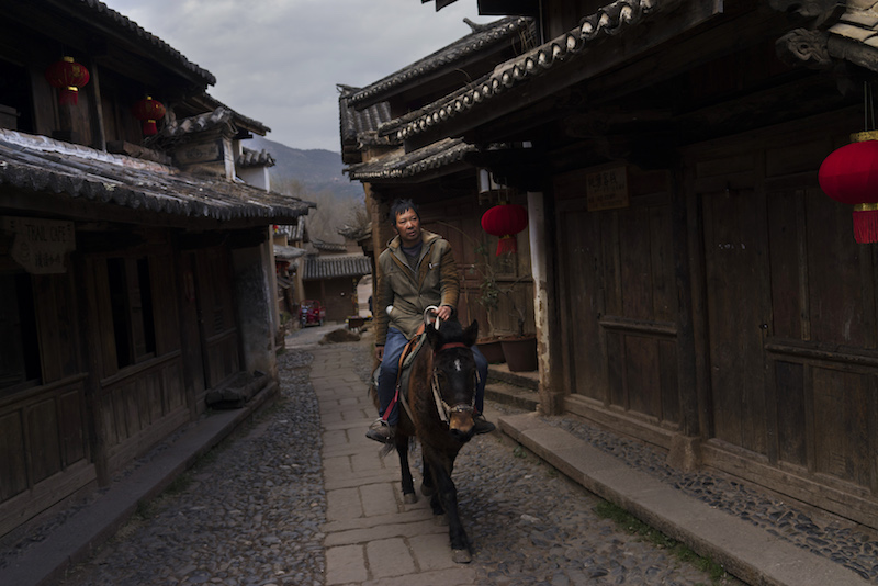A man rides a horse through an alley leading to the square of Sideng Village in the old town centre of Shaxi, China, January 28, 2016. — Picture by Adam Dean/The New York Times