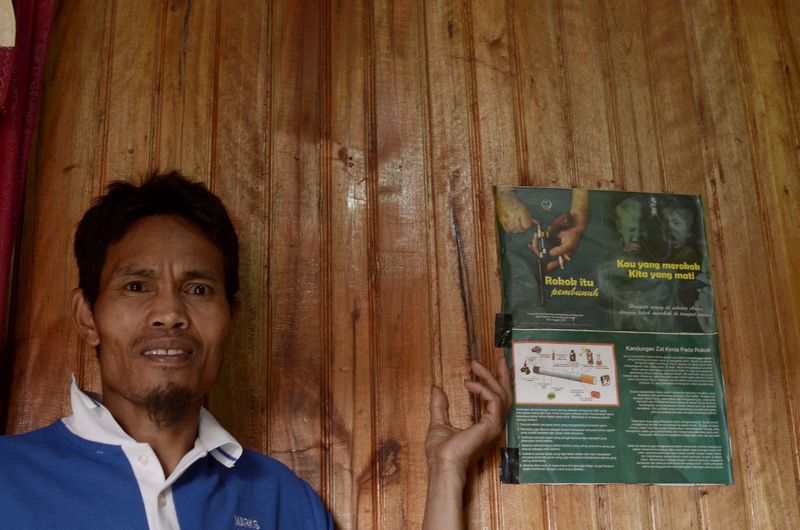 This photo taken on December 20, 2015 shows village head Abdul Wahid, standing next to an anti-smoking campaign poster at his house in Bone-Bone village, Enrekang, South Sulawesi. u00e2u20acu201d AFP pic 
