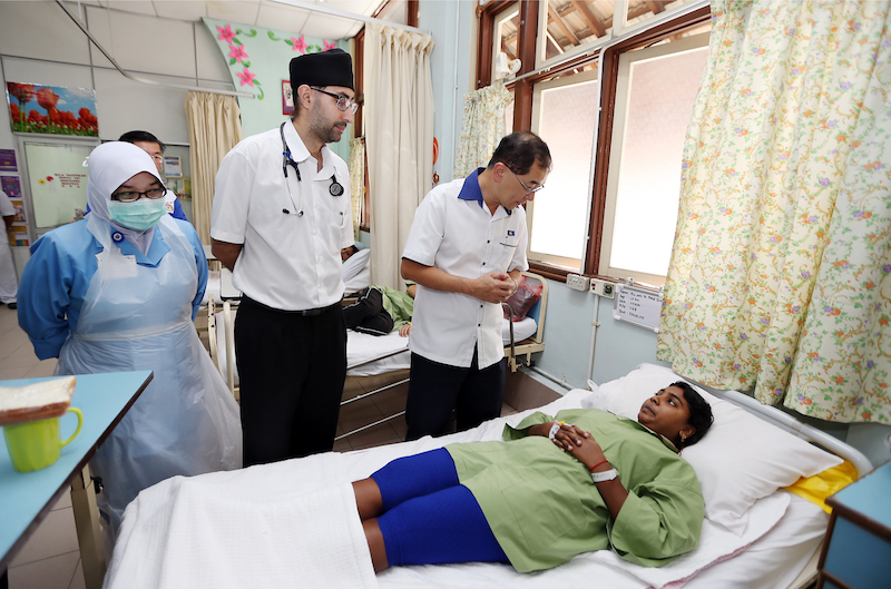 Dr Mah visiting one of the food poisoning victims at Batu Gajah Hospital yesterday. Looking on is Raja Permaisuri Bainun Hospital visiting physician Dr Harnek Singh. u00e2u20acu201d Picture by Malay Mail