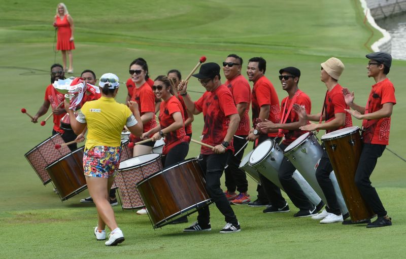 South Koreau00e2u20acu2122s Jang Ha-Na (L, in yellow) holds her trophy and dances to the music after winning the HSBC Womenu00e2u20acu2122s Champions golf tournament at the Sentosa Golf Club in Singapore March 6, 2016. nROSLAN RAHMAN / AFP