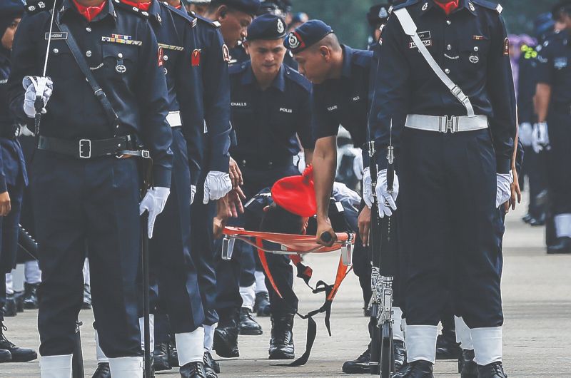 Medical personnel attend to an FRU personnel who fainted in the scorching heat during yesterdayu00e2u20acu2122s Police Day celebrations. u00e2u20acu201d Picture by Firdaus Latif