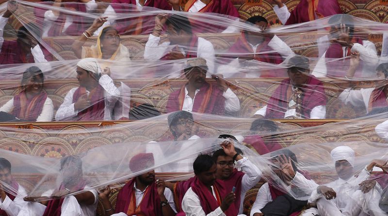 Participants cover themselves with plastic sheets as the rains come down, heightening the concerns of the environmentalists.