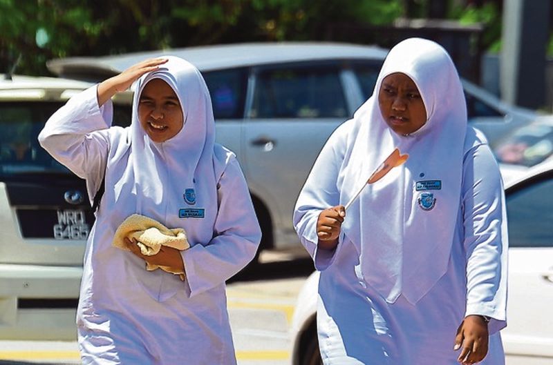 Two SMK Raja Muda Shah Alam students feel the heat as they leave for home in Selangor yesterday. u00e2u20acu2022 Picture by Zuraneeza Zulkifli
