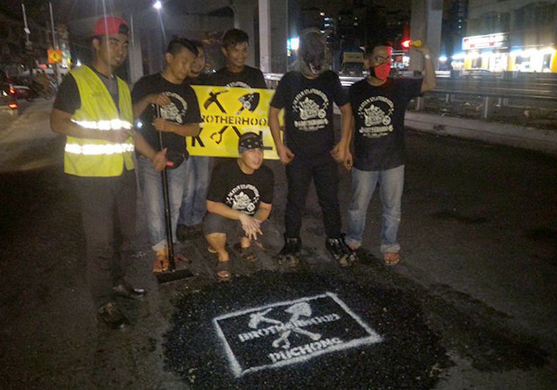 Six members of the Brotherhood's Puchong unit with the pothole they just covered over.