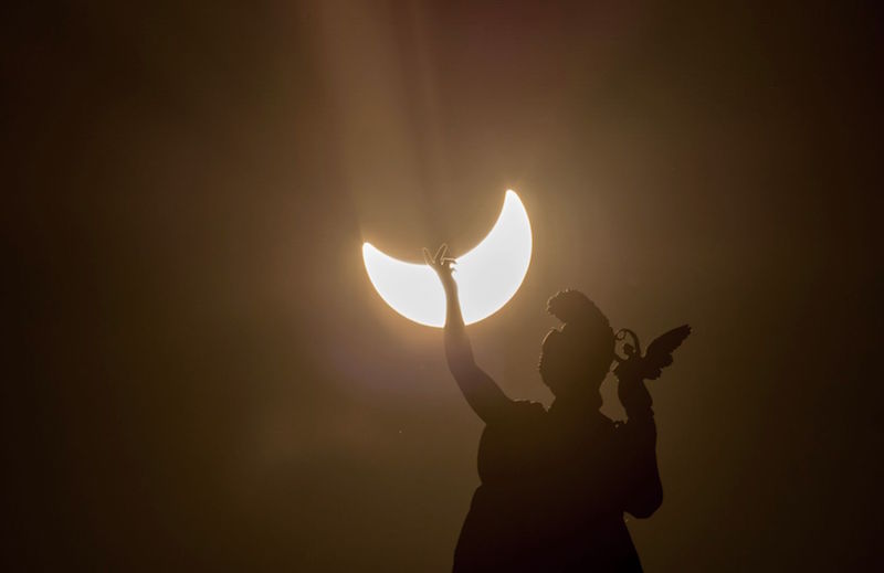 A partial solar eclipse is visible over a statue located at the rooftop of Austrian Art History Museum in Vienna March 20, 2015. u00e2u20acu201d AFP pic