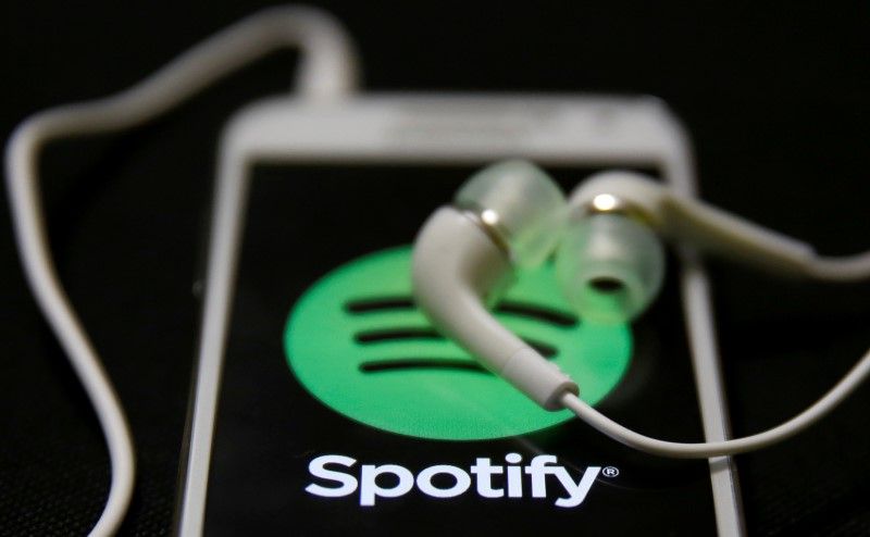 Earphones are seen on top of a smart phone with a Spotify logo on it, in this picture released March 30, 2016. u00e2u20acu201d Reuters pic