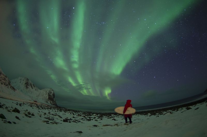 A surfer stands by northern lights (aurora borealis) on the snow covered beach of Unstad, on Lofoten Island, Arctic Circle. u00e2u20acu201d AFP pic