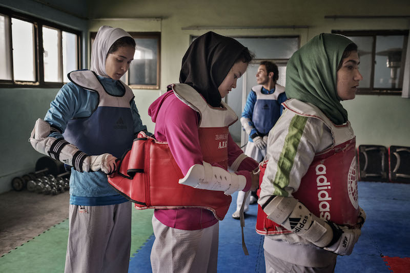 (From left) Somaya Ghulami, Tayeba Akbari and Nilu Ahmadi, all on the national taekwondo women’s team, help each other with sparring pads while training at a gym in Kabul March 16, 2016. — Picture by Adam Ferguson/The New York Times