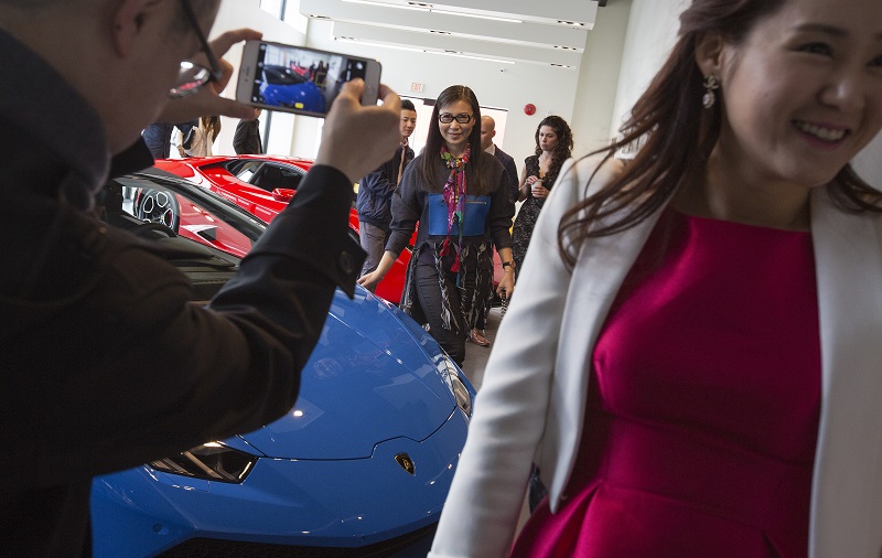Paul Oei photographs his wife Loretta Lai with a new car during a reception at a Lamborghini dealership in Vancouver, British Columbia, March 19, 2016. — Picture by Ruth Fremson/The New York Times