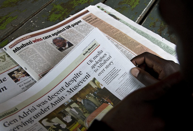 A person reads a news story about Britain's Daily Mail in the Ugandan daily newspaper, The New Vision, on July 31 2013 in Kampala. u00e2u20acu201d AFP pic