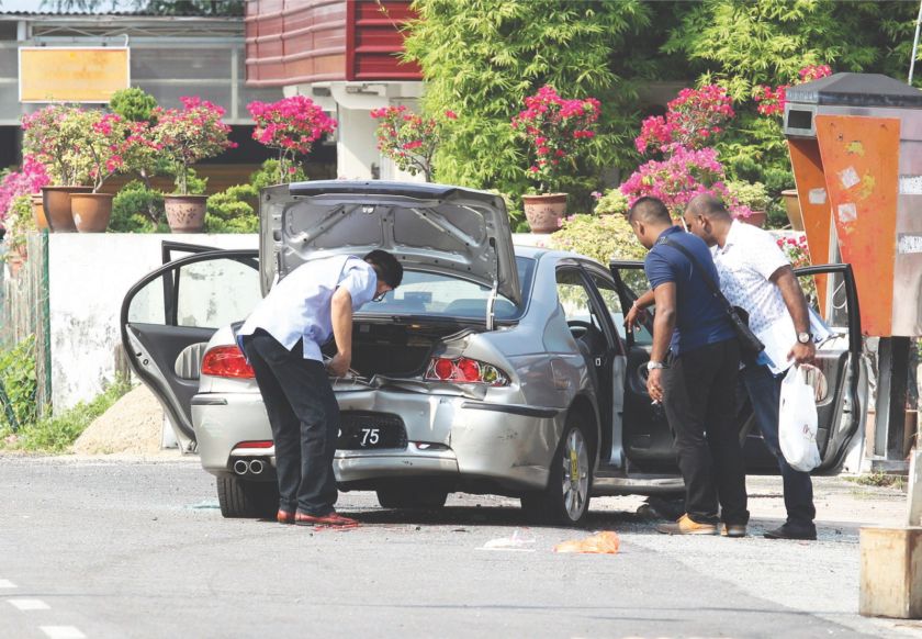 Police personnel examine one of the cars after the shooting yesterday. u00e2u20acu201d Picture by Sin Chew