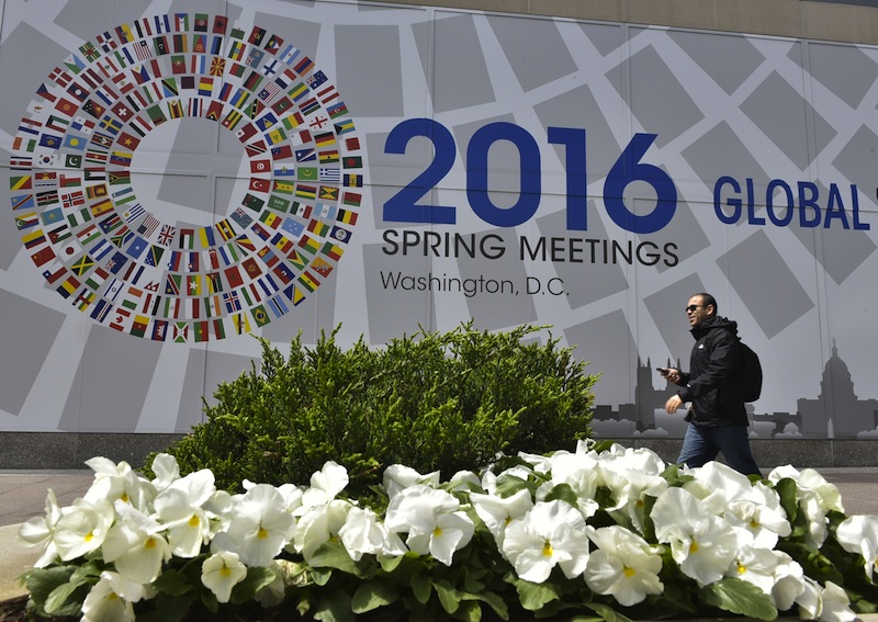 A man pass a sign announcing the 2016 spring meetings of the International Monetary Fund and World Bank outside of the IMF headquarters on April 10, 2016 in Washington, DC. u00e2u20acu201d AFP pic
