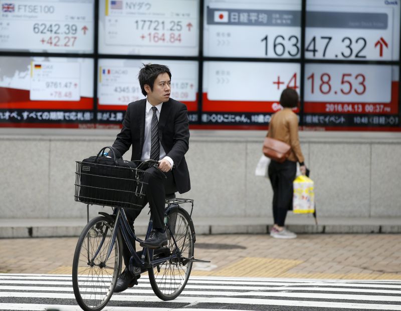 A man cycles in front of an electronic board showing Japan's Nikkei average outside a brokerage in Tokyo, Japan, April 14, 2016. u00e2u20acu2022 Reuters pic 