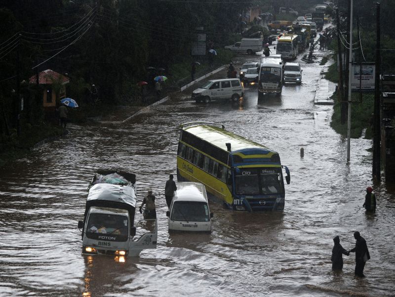 People attempt to cross through a flooded section of road, as others climb out of vehicles on April 29, 2016, in the Kenyan capital Nairobi that has been hit by heavy downpours as the long rains season starts. nTONY KARUMBA / AFPn
