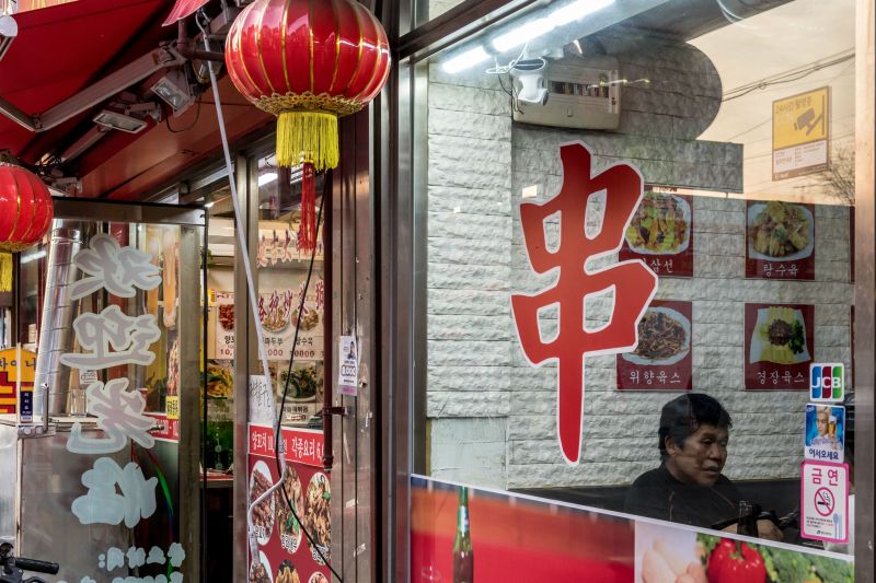 Chinese characters on a restaurant window announce that Korean lamb skewers are served at the restaurant. 