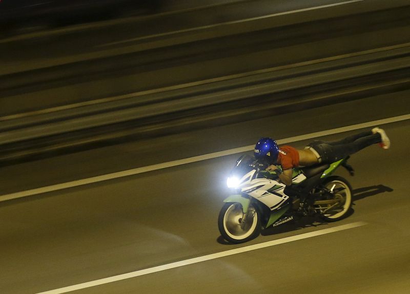 A motorcyclist performs the superman stunt on a highway in Kuala Lumpur.