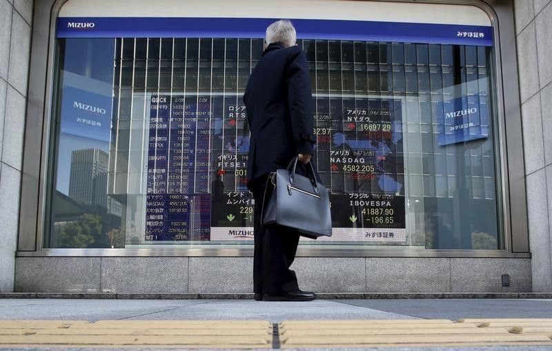 A pedestrian stands to look at an electronic board showing the stock market indices of various countries outside a brokerage in Tokyo February 26, 2016. u00e2u20acu201d Reuters pic