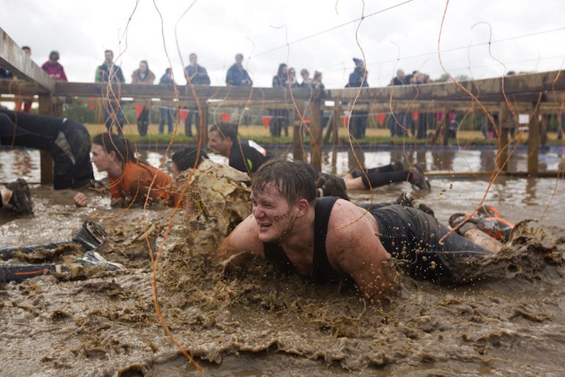 Participants crawl through mud during the Tough Mudder endurance race in Henley on Thames, west of London, April 26, 20— AFP pic