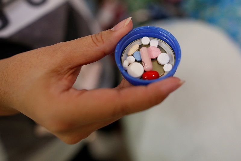 Supapan Pullbangyung, 39, holds a cup containing medicines for her father, Serm Pullbangyung, 75, at her house in Nonthaburi, Thailand April 24, 2016. u00e2u20acu201d Reuters pic