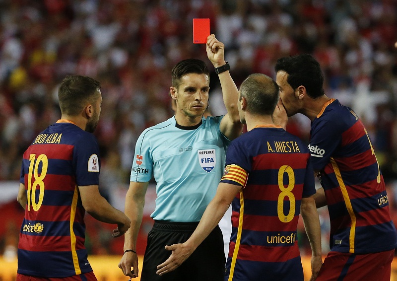 Referee Carlos Del Cerro Grande shows a red card to Javier Mascherano as Andres Iniesta remonstrates in Madrid, Spain May 22, 2016.