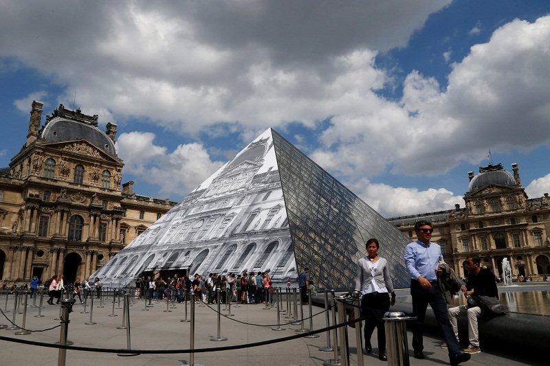 Tourists walk near French artist JRu00e2u20acu2122s latest work, an image of the facade of Parisu00e2u20acu2122 Louvre that covers the museumu00e2u20acu2122s Pyramid entrance in Paris, France May 27, 2016. u00e2u20acu201d Reuters pic
